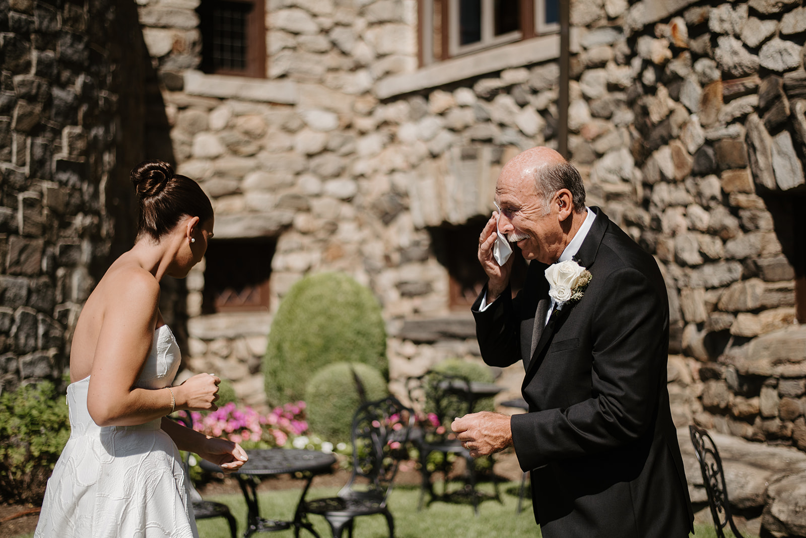 Emotional father wiping a tear while smiling at his daughter during their first look in the garden.